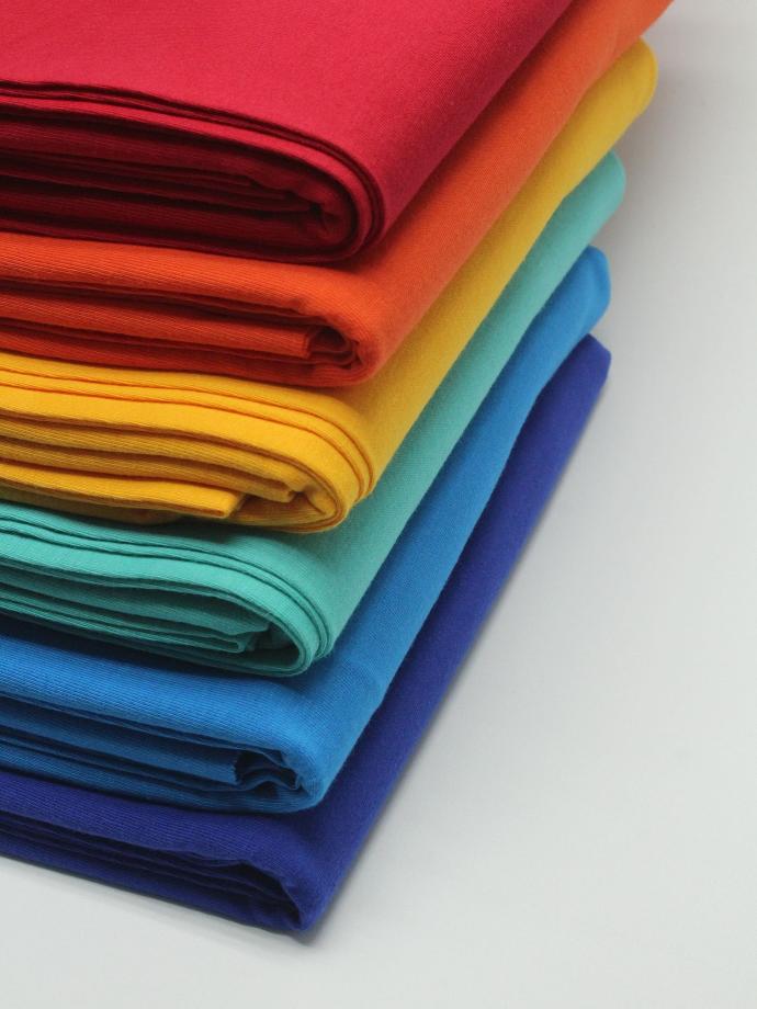 a stack of bright colored cloths on a white surface