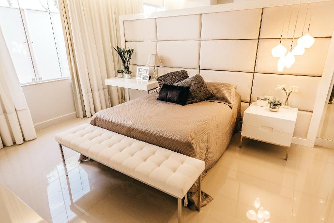 white nightstand and tufted white fabric bench beside bed